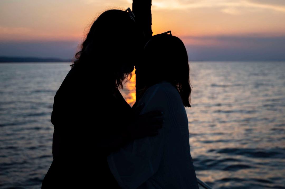 Silhouette of a couple kissing on a boat against a dusk sky and calm sea, a moment from a sunset sailing cruise Halkidiki