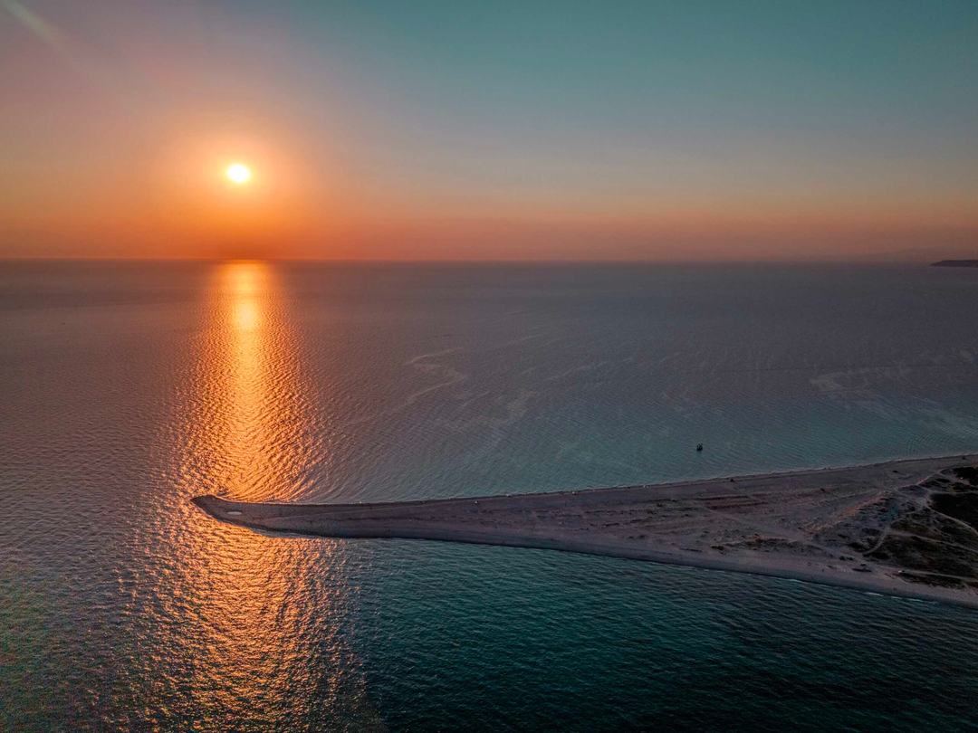 Aerial sunset over a calm sea off Kassandra Halkidiki, the sun’s reflection leading to the tip of a narrow sand spit